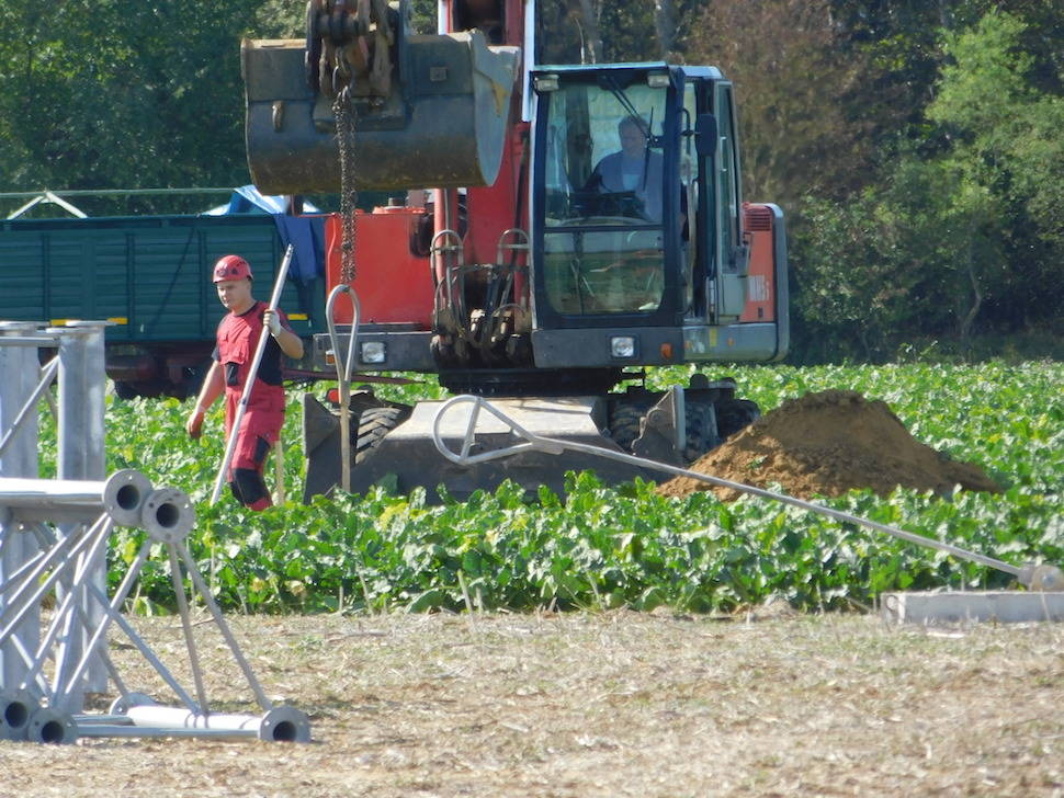 Ein Arbeiter-Team bereitet den Boden vor. Ein kleiner Bagger reicht, um das kleine Fundament für den Windmessmast zu graben.