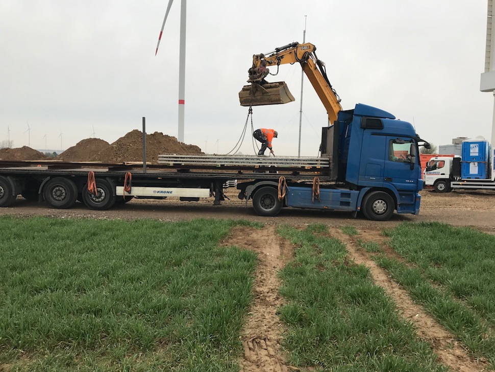 a truck arrives with the formwork elements, a worker stands on the truck and unlocks the cargo