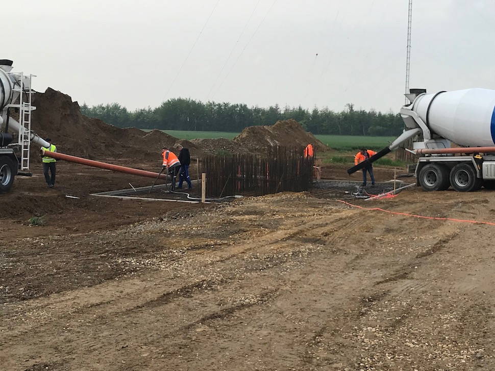 five workers filled the crane foundation with concrete, two truck mixers drove backwards to the foundations, the workers attach the pipes to the truck mixer