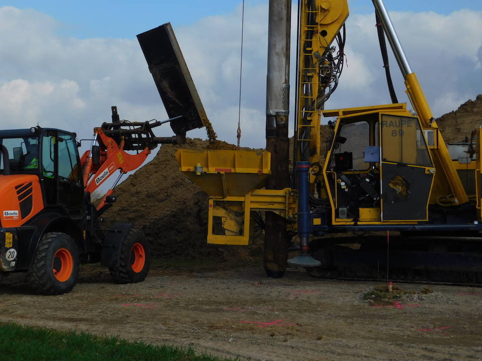 A wheel loader delivers the waste material into the hopper of the machine